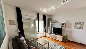 Una sala de estar moderna con un sofá, televisor y puerta corrediza de vidrio.