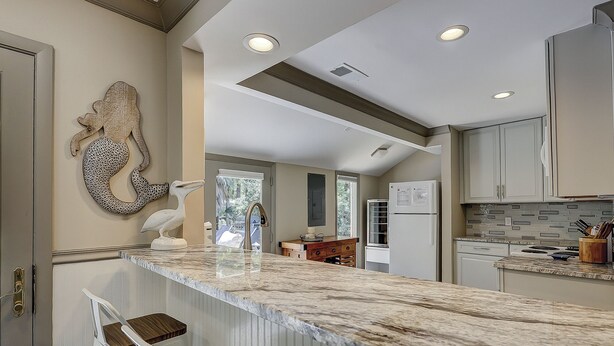 A kitchen with a marble countertop, white cabinetry, and a large decorative pelican sculpture. - Sunset Rentals | 5 Rice Lane | Dog Friendly (Hilton Head Island)