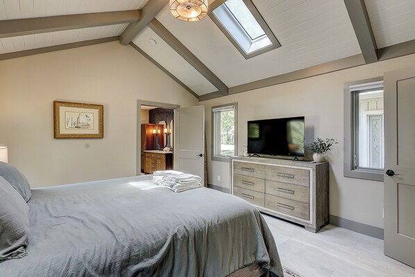 A bedroom with a bed, a TV, a dresser, and a skylight. - Sunset Rentals | 5 Rice Lane | Dog Friendly (Hilton Head Island)