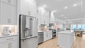 Una cocina moderna con armarios blancos, electrodomésticos de acero inoxidable y piso de madera.