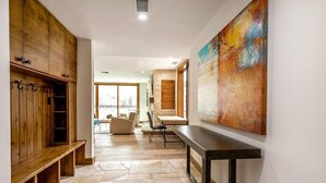 A spacious hallway with wooden cabinets, a dining area, and a large abstract painting on the wall. - Luxe 4 Bedroom Beaver Creek Lodge Condo With ski in, ski out Access (Avon)