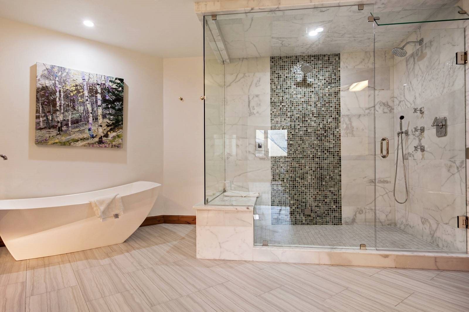 A modern bathroom with a freestanding bathtub, a glass-enclosed shower, and a mosaic wall.