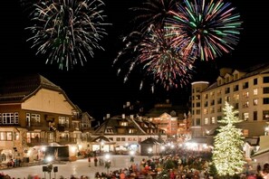 Una plaza de pueblo con gente, edificios y un árbol de Navidad.