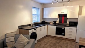 A compact kitchen with a washing machine, a microwave, and a sink. - Ground Floor Apartment - Cloisters Coastal Escape (East Riding of Yorkshire)