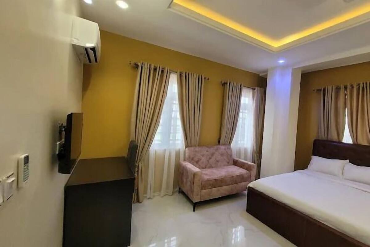 A hotel room with a bed, a chair, a desk, and a TV.