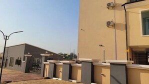 A modern building with a flat roof, a gated entrance, and a clear sky. - Riverview Hotel and Suites (Ife)