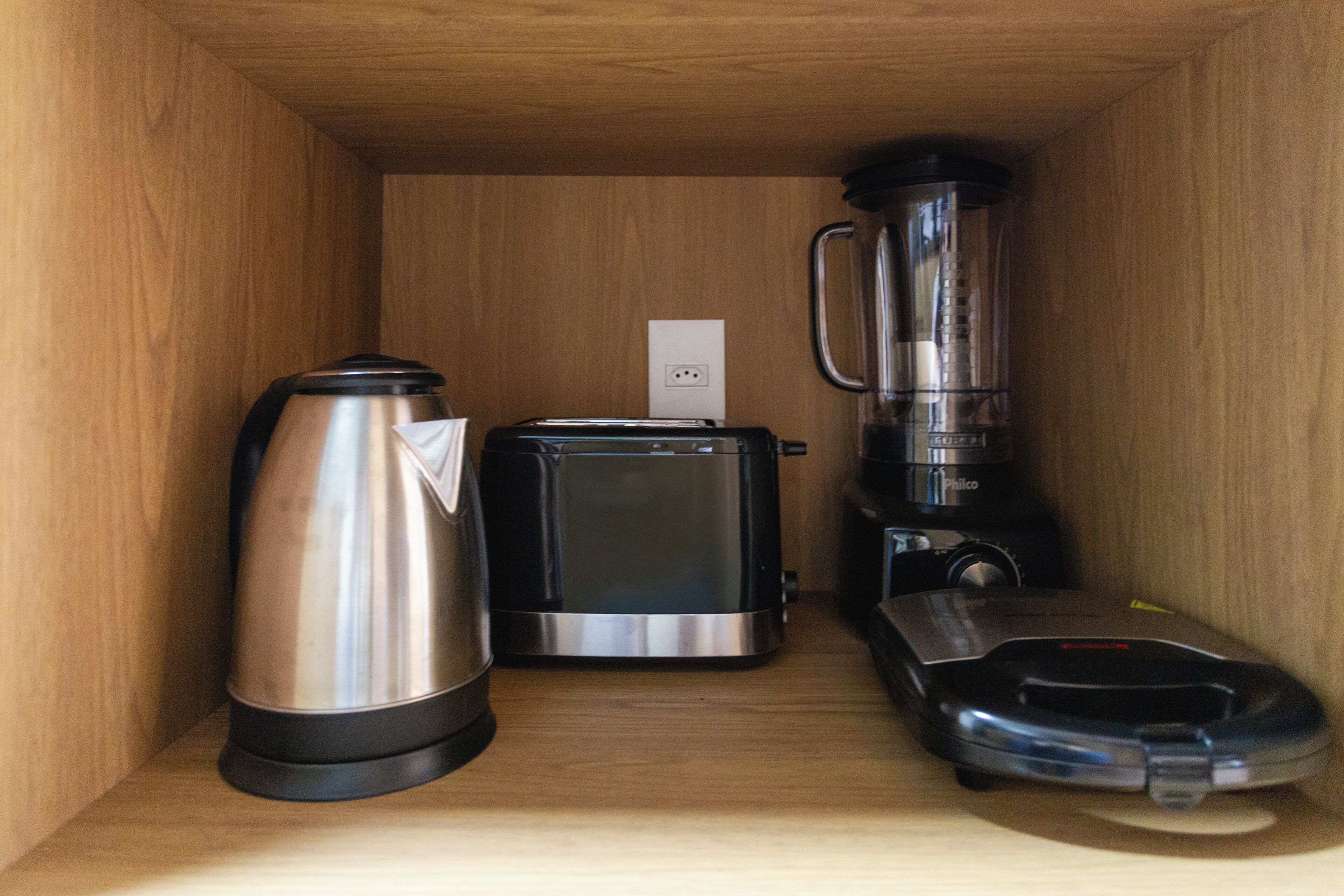 A compact kitchenette with a coffee maker, toaster, and blender.