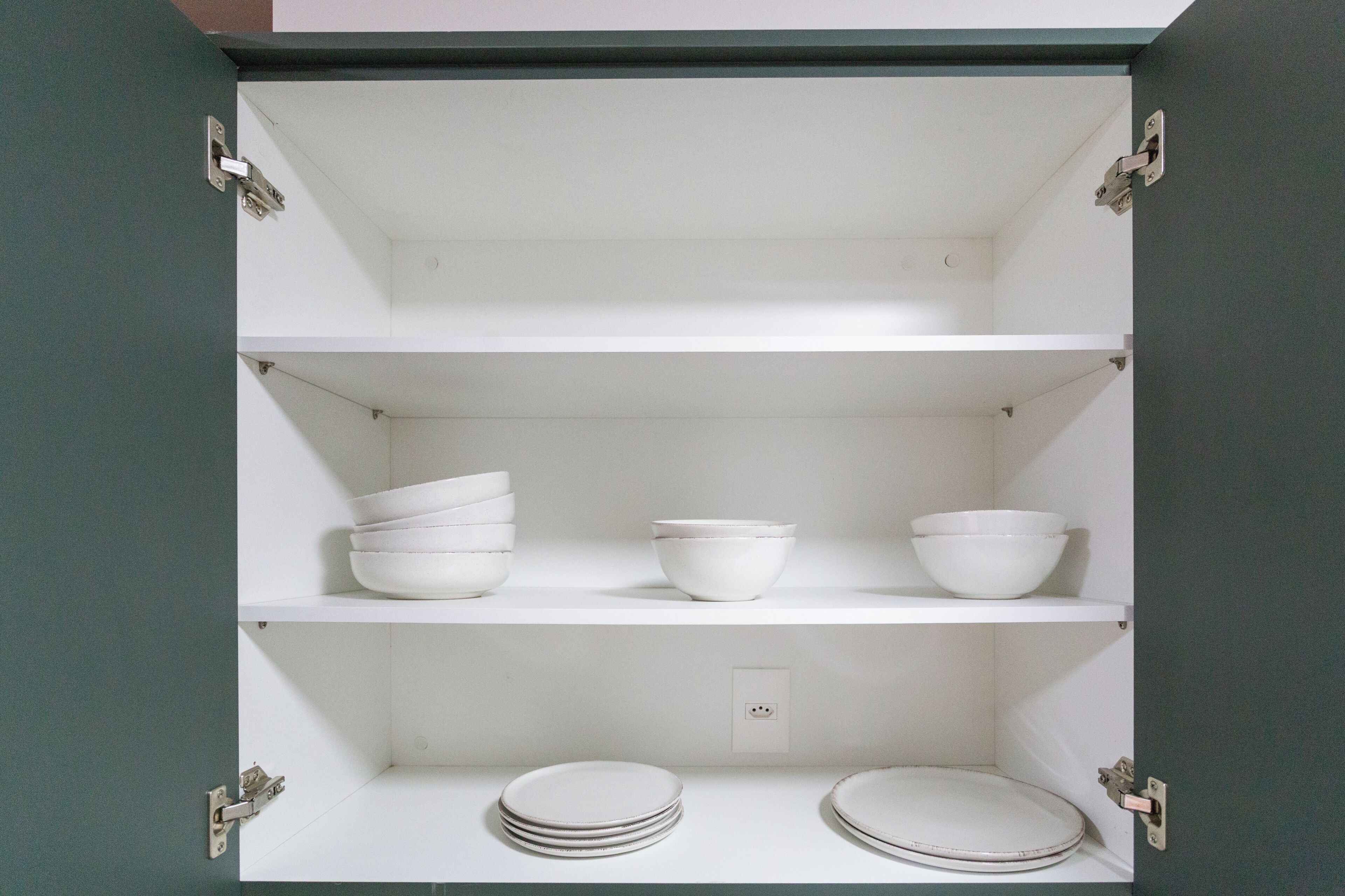 A cabinet with three shelves, each containing bowls and plates.