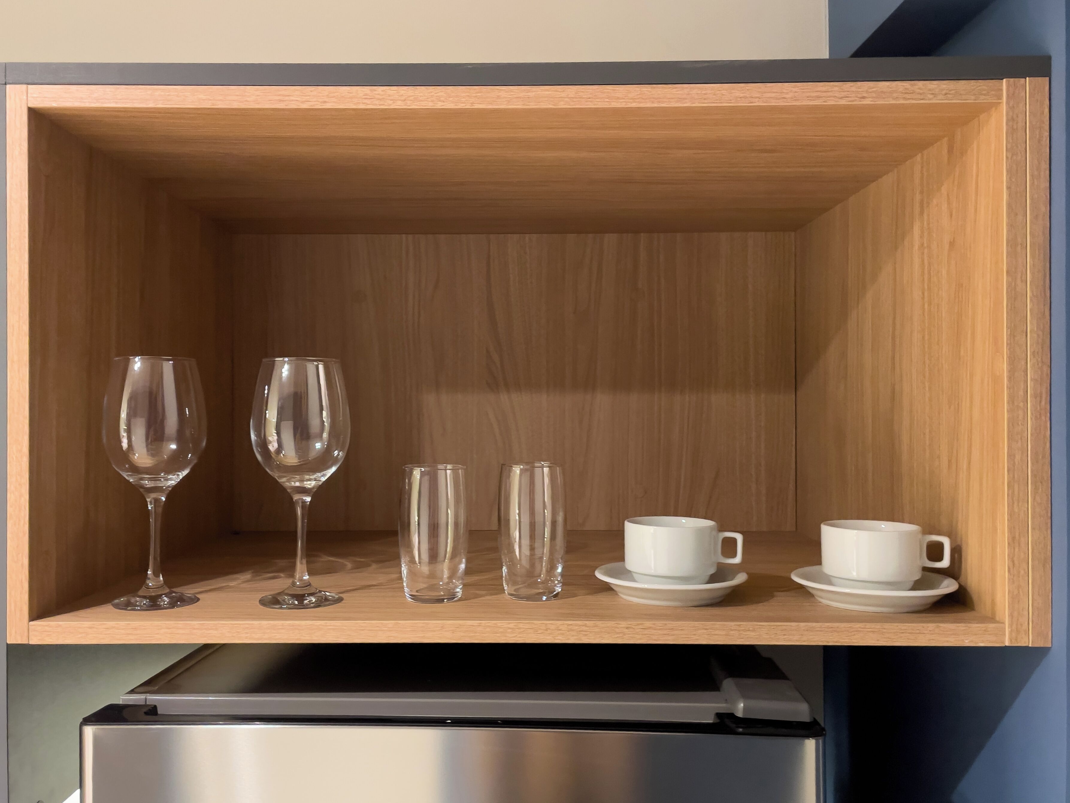 Een houten kastje met wijnglazen en kopjes.