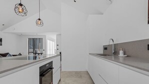 Una cocina moderna con armarios blancos, una isla central e iluminación colgante.