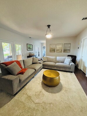 A living room with a sectional sofa, a round coffee table, and a chandelier.