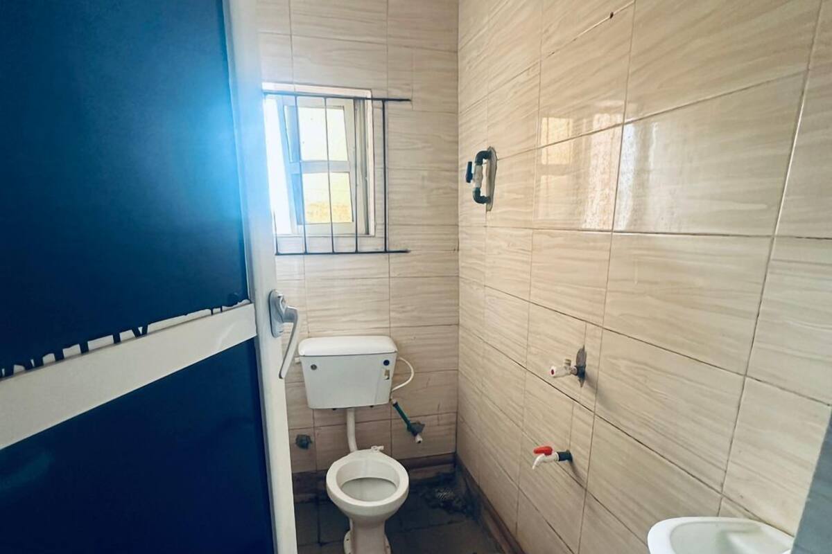 Une petite salle de bain étroite, avec des toilettes, un lavabo et une fenêtre.