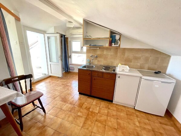 A compact kitchen with a sink, wooden cabinets, and a white refrigerator. - Apartment Luky 9 (Dramalj)