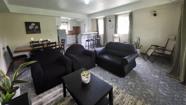 A living room with a sofa, a coffee table, and a dining area with chairs and a table. - Fully furnished 3BR home in Sylvania with Wi-Fi, AC, kitchen & serene views. (Sylvania)
