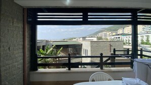 En balkon med udsigt over by og bjerglandskab.