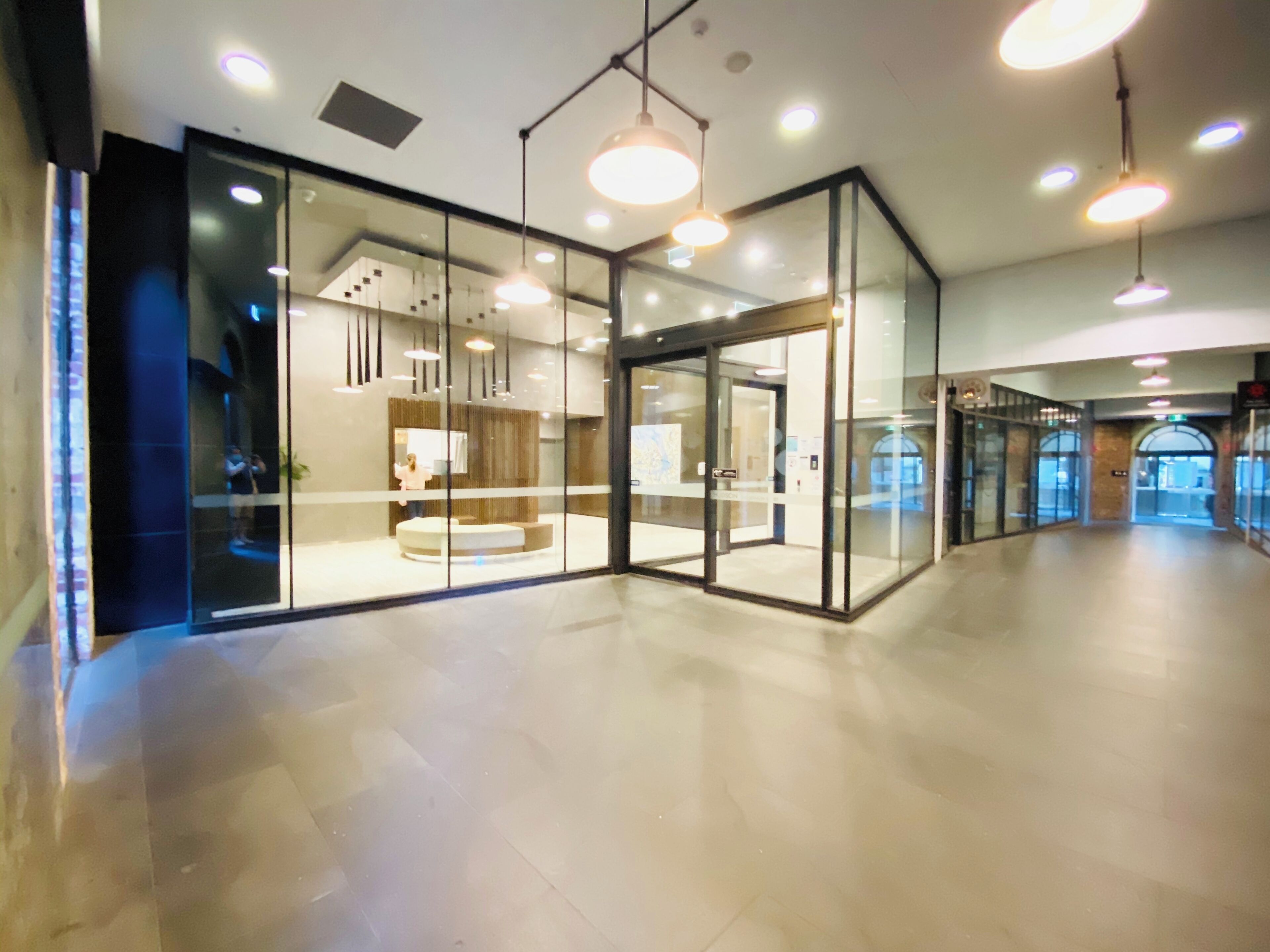 A modern lobby with glass walls, recessed lighting, and a central seating area.