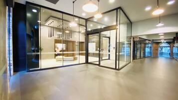 A modern lobby with glass walls, recessed lighting, and a central seating area.