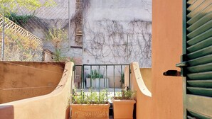A narrow outdoor corridor with steps leading to a gated area, surrounded by a concrete wall and a metal fence. - Cistern Elegant Comfort 2bdr (Roma)
