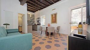 A living room with a teal sofa, a dining area with a table and chairs, and a kitchen in the background. - Cistern Elegant Comfort 2bdr (Roma)