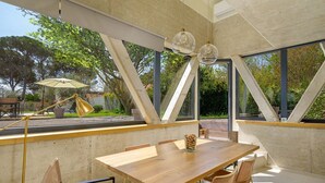 A modern dining area with a wooden table and chairs, large windows, and a view of the outdoors. - Seaside Luxury Immersed in Nature (Valbandon)