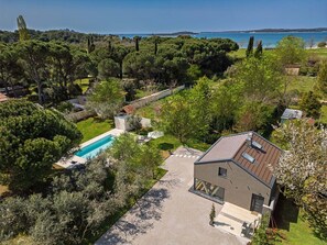 A modern house with a swimming pool, surrounded by lush greenery and a view of the sea. - Seaside Luxury Immersed in Nature (Valbandon)