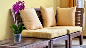 A wooden bench with cushions and a potted plant. - B&B Holiday (Torre Annunziata)