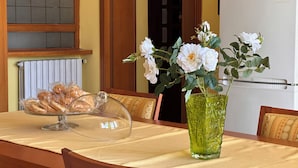 A dining table with a clear glass dome cover, a green vase with white flowers, and a bread basket. - B&B Holiday (Torre Annunziata)