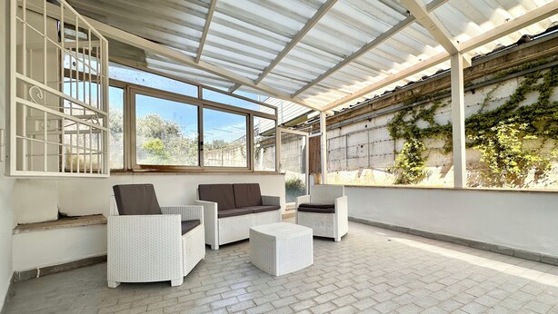 A covered outdoor seating area with wicker furniture and a brick floor. - B&B Holiday (Torre Annunziata)