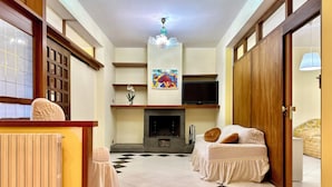 A hotel room with a checkered floor, a fireplace, a television, and a bed with pillows. - B&B Holiday (Torre Annunziata)