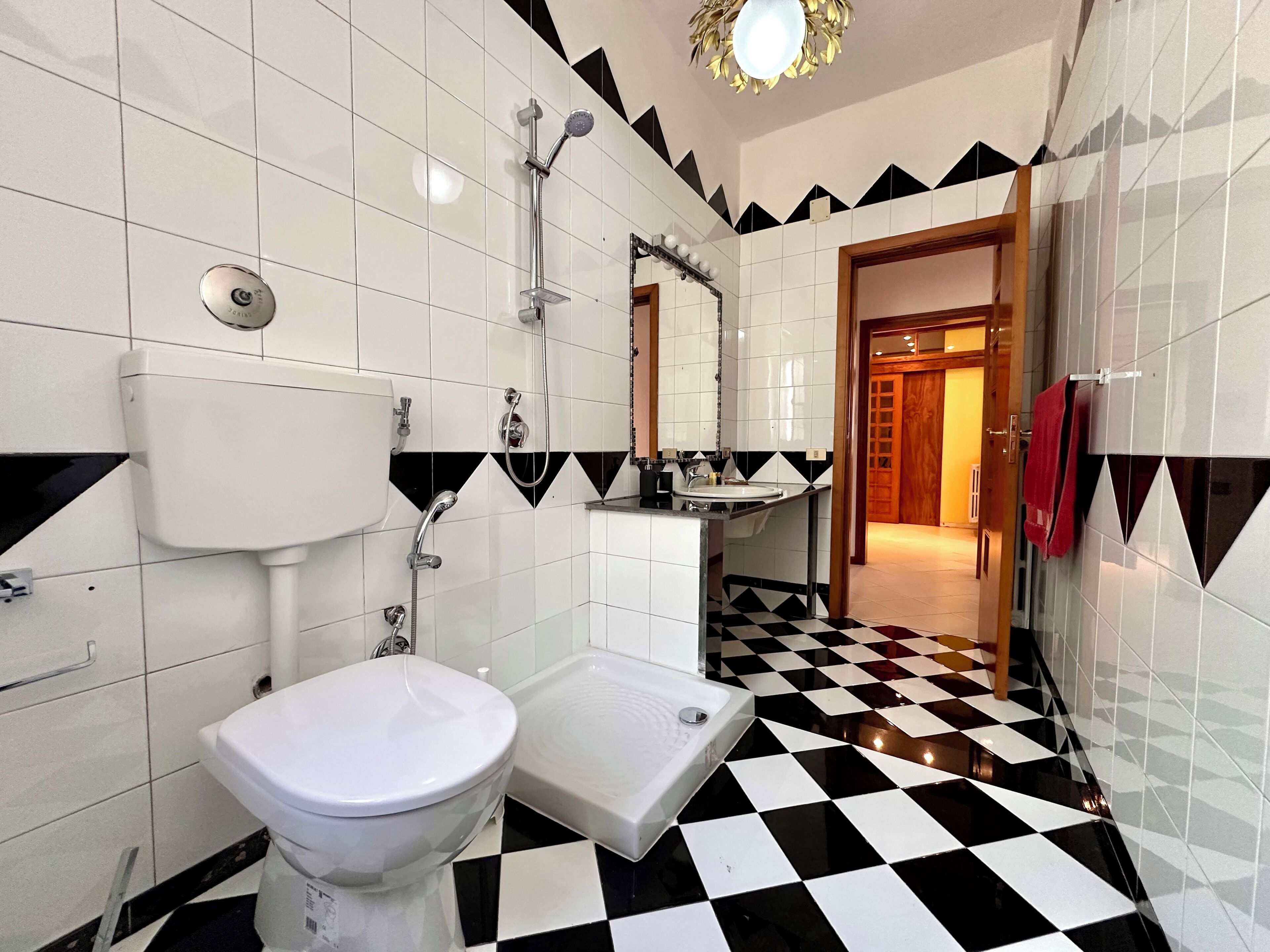 A bathroom with a toilet, sink, and shower. The floor has a black and white checkered pattern.