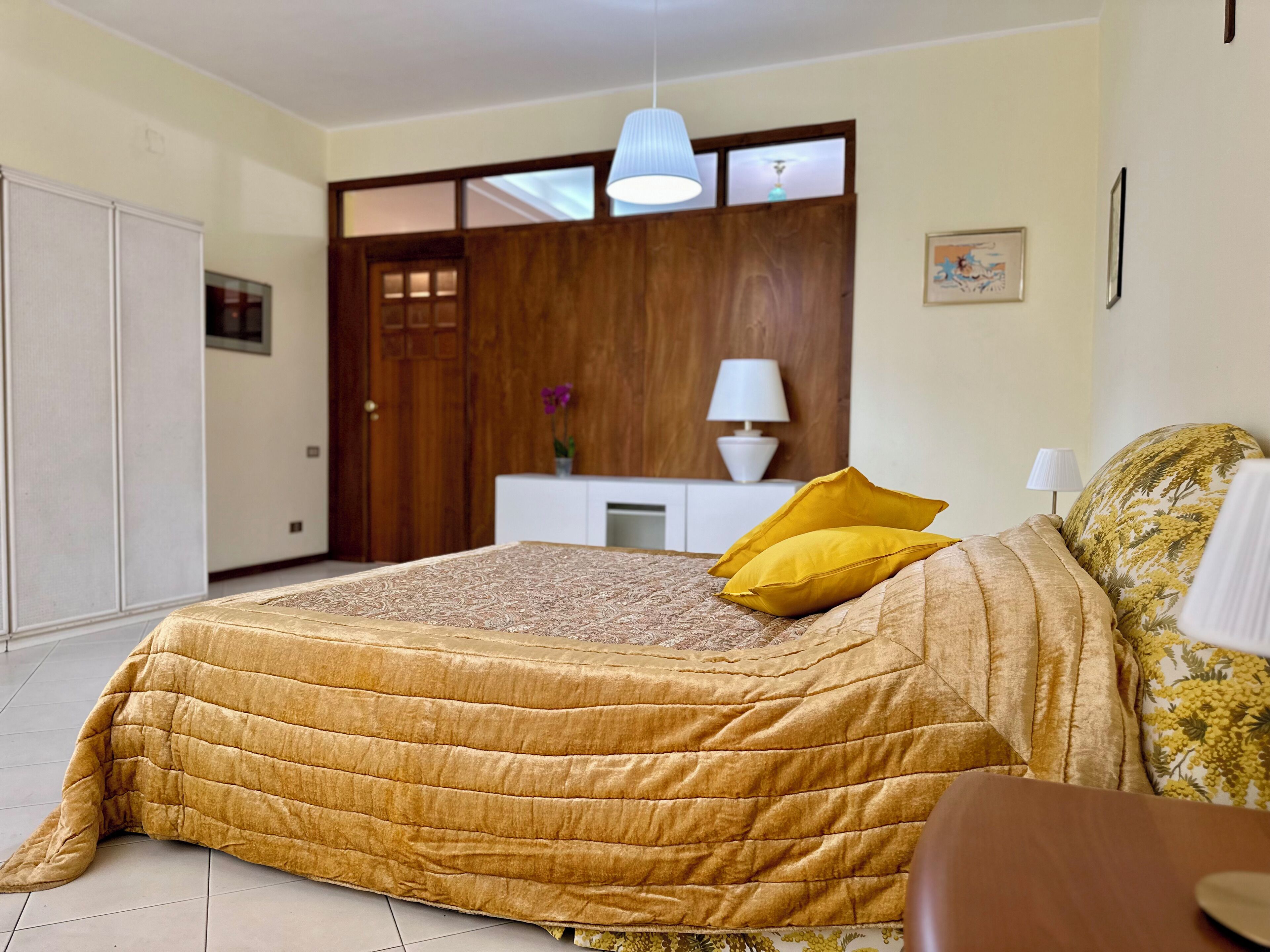 Ein Schlafzimmer mit einem großen Bett, einem Holzschrank, einem weißen Schrank und einer Pendelleuchte.