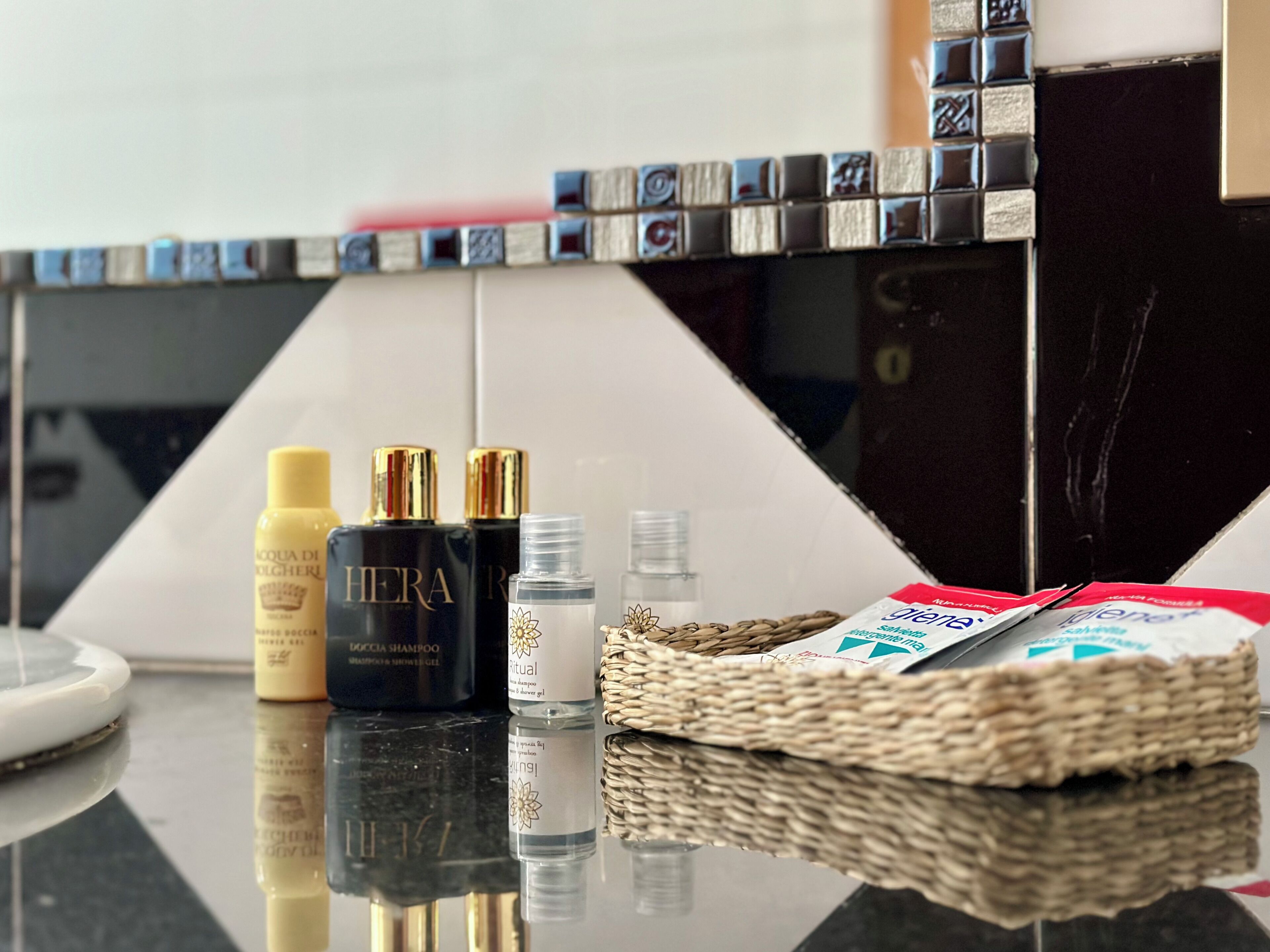 Una encimera de baño con artículos de aseo, incluyendo una botella de champú, una de acondicionador y un frasco pequeño de loción.