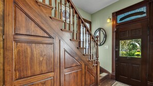 Un escalier en bois avec une rampe, une porte dotée d’un panneau de verre et un tapis sur le sol.