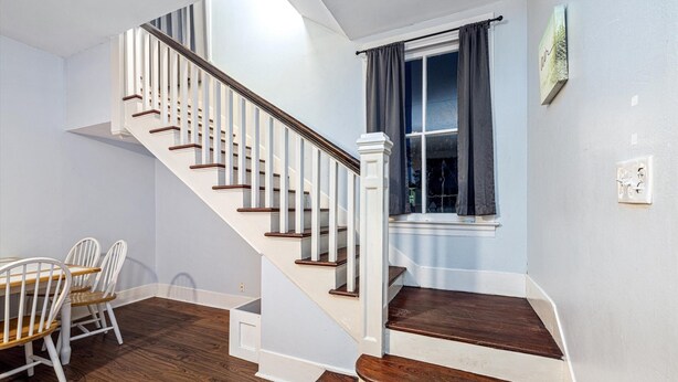 Un escalier avec des marches en bois et des rampes blanches menant à un palier.