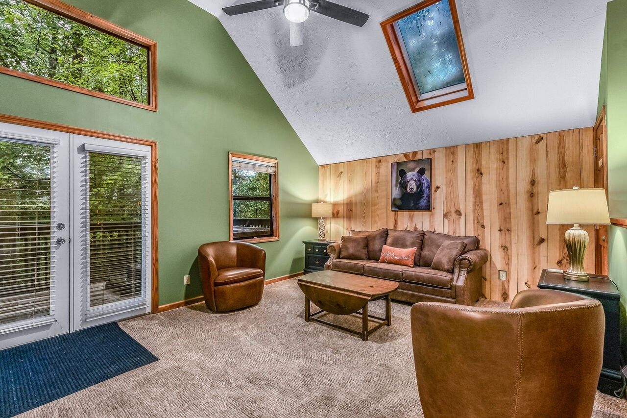 A living room with a ceiling fan, a sofa, a coffee table, and a fireplace.