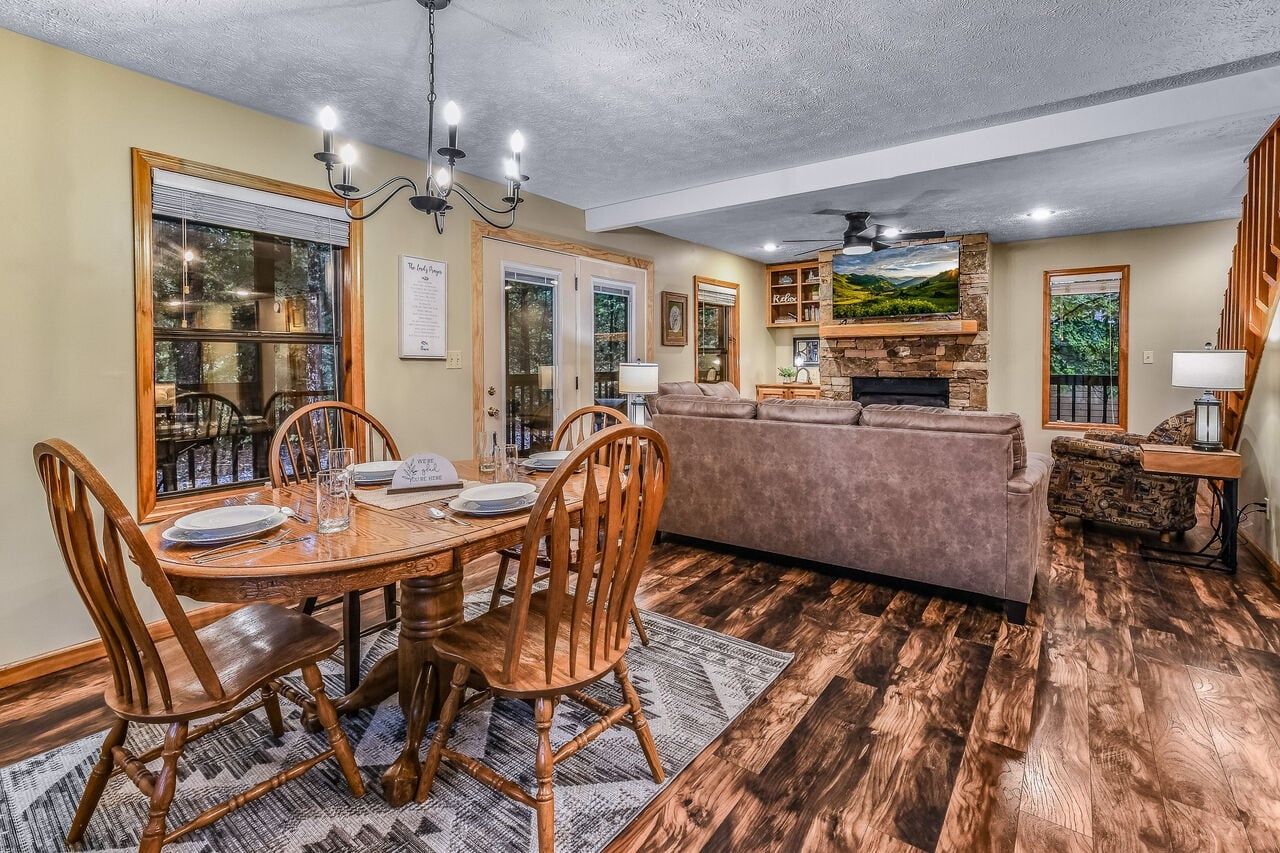 A dining area with a wooden table and chairs, a sofa, and a fireplace.