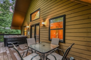 An outdoor patio with a glass table and chairs, wooden deck, and a bench. - Count Your Blessings 3 Bedroom Home (Pigeon Forge)