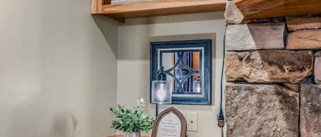 A wooden shelf with books, a framed picture, a small potted plant, and a framed certificate on a wooden table.