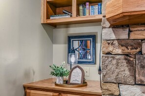 Ein Holzregal mit Büchern, einem gerahmten Bild, einem kleinen Topfpflanzen und einem gerahmten Zertifikat auf einem Holztisch.