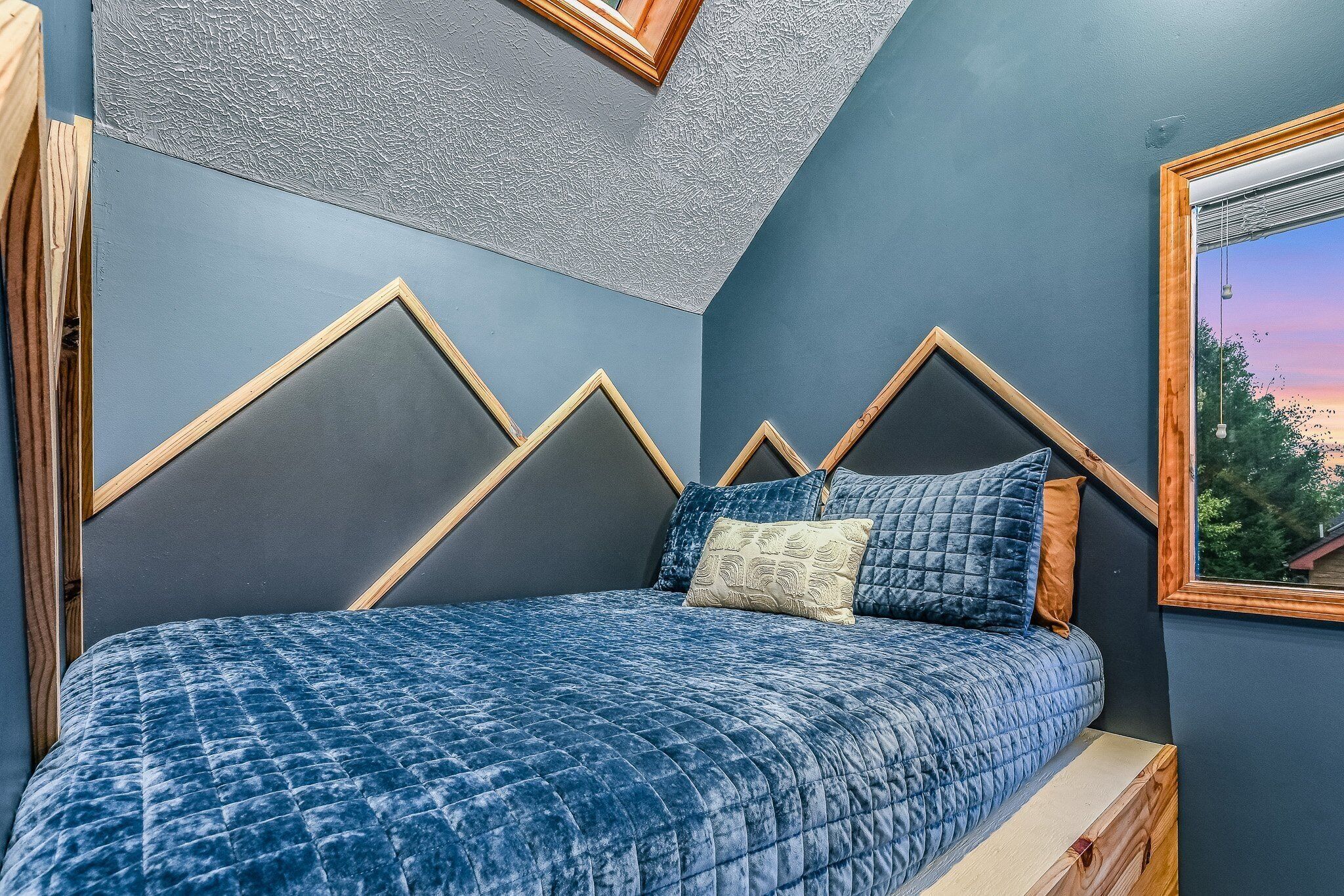 A bedroom with a bed, wooden headboard, and a window with a view.