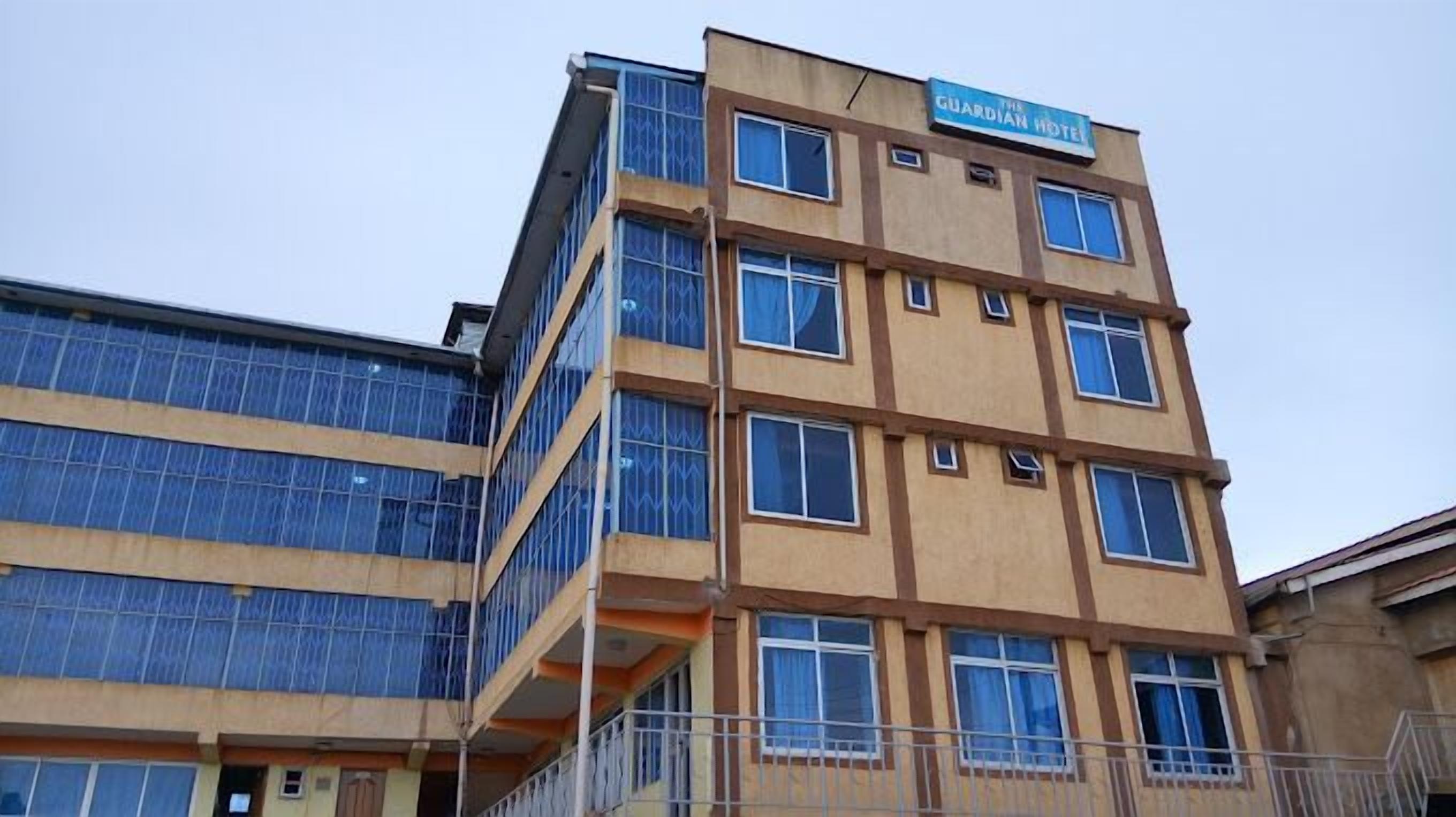 A multi-story building with a sign reading "The Guardian Hotel".