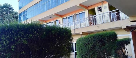 A multi-story building with balconies, a gravel driveway, and well-maintained greenery.