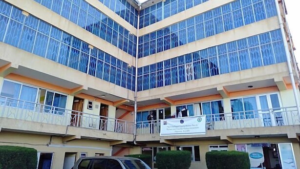 A multi-story building with large glass windows, a central atrium, and a sign indicating it is a government facility. - The Guardian Hotel Nyamira (Nyamira)