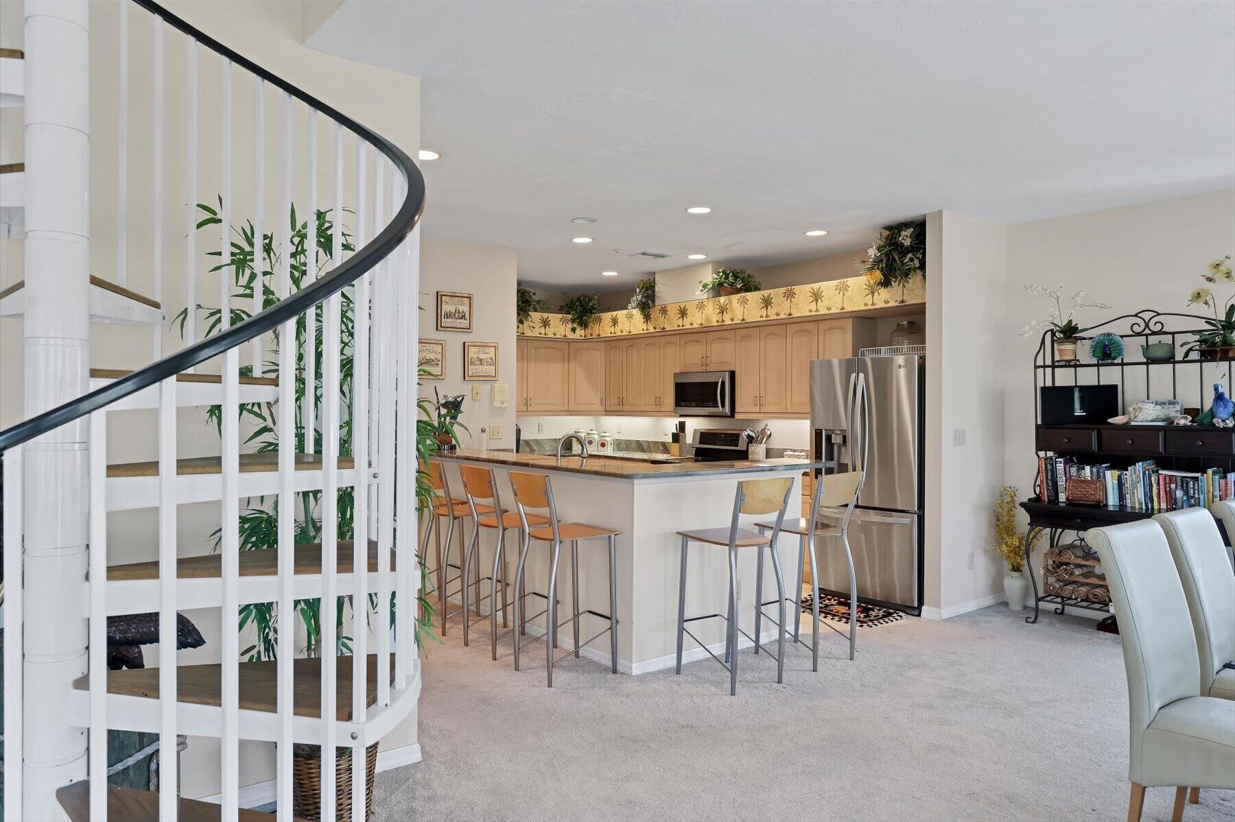 Cozinha moderna com ilha central, banquetas e geladeira embutida.