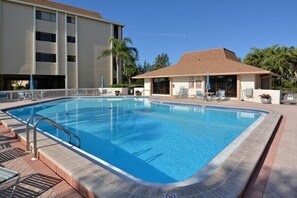 A rectangular pool with a tiled edge, surrounded by a patio area with lounge chairs and umbrellas. - 2/2 Bay Front Condo, Pool, Private Beach Access (Longboat Key)