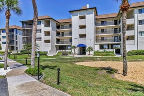 A multi-story residential building with balconies, a covered entrance, and a landscaped courtyard with palm trees. - 2/2 Bay Front Condo, Pool, Private Beach Access (Longboat Key)