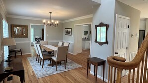A spacious dining area with a wooden table and chairs, a chandelier, and a view into the kitchen. - Charming 4-bedroom House on beautiful farm in Clear Brook with lovely views (Clear Brook)