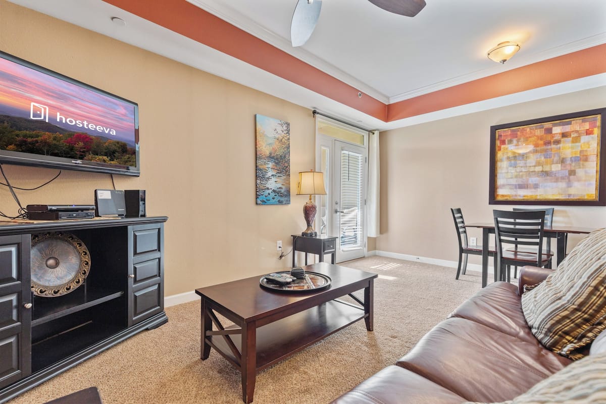 A living room with a television, a dining area, and a sofa.