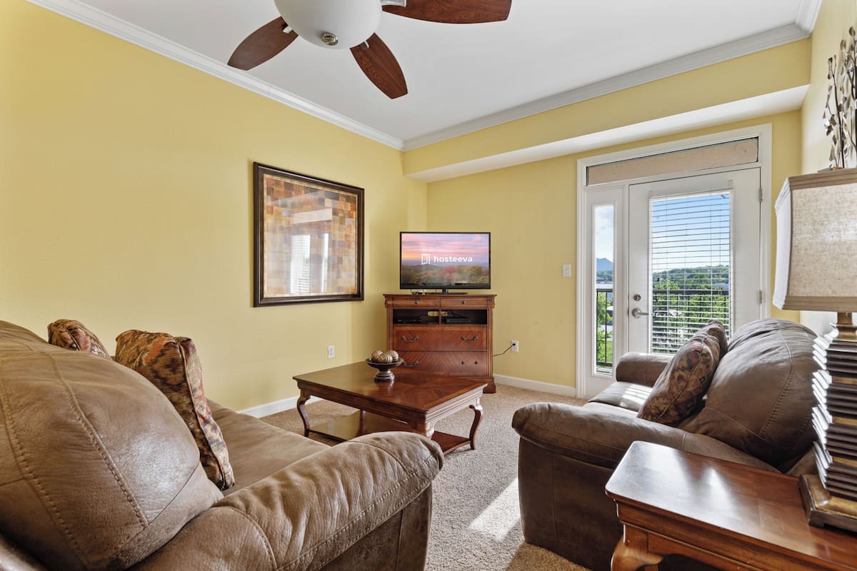 A living room with a ceiling fan, a television, a wooden cabinet, and a sofa.