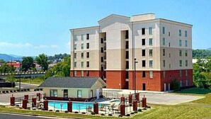 A multi-story hotel with a pool area, featuring a two-story building with a flat roof and a smaller attached structure with a sloped roof.